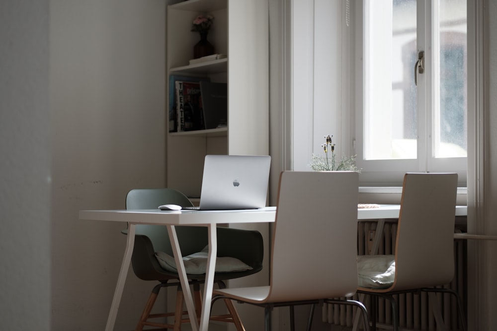 silver macbook on white table