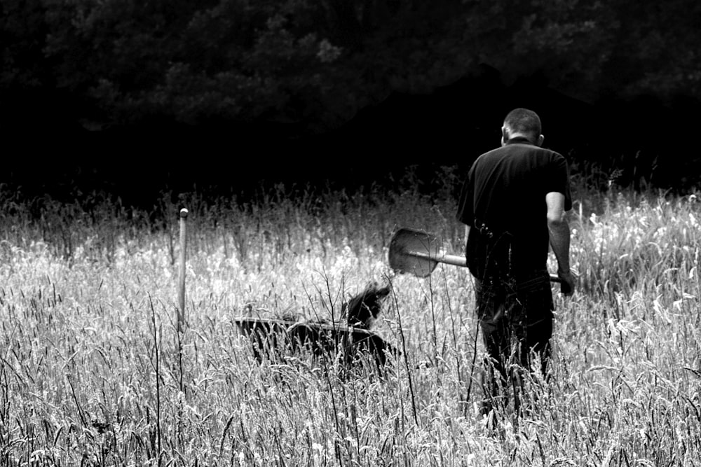 Hombre con camisa negra y pantalones de pie en el campo de hierba