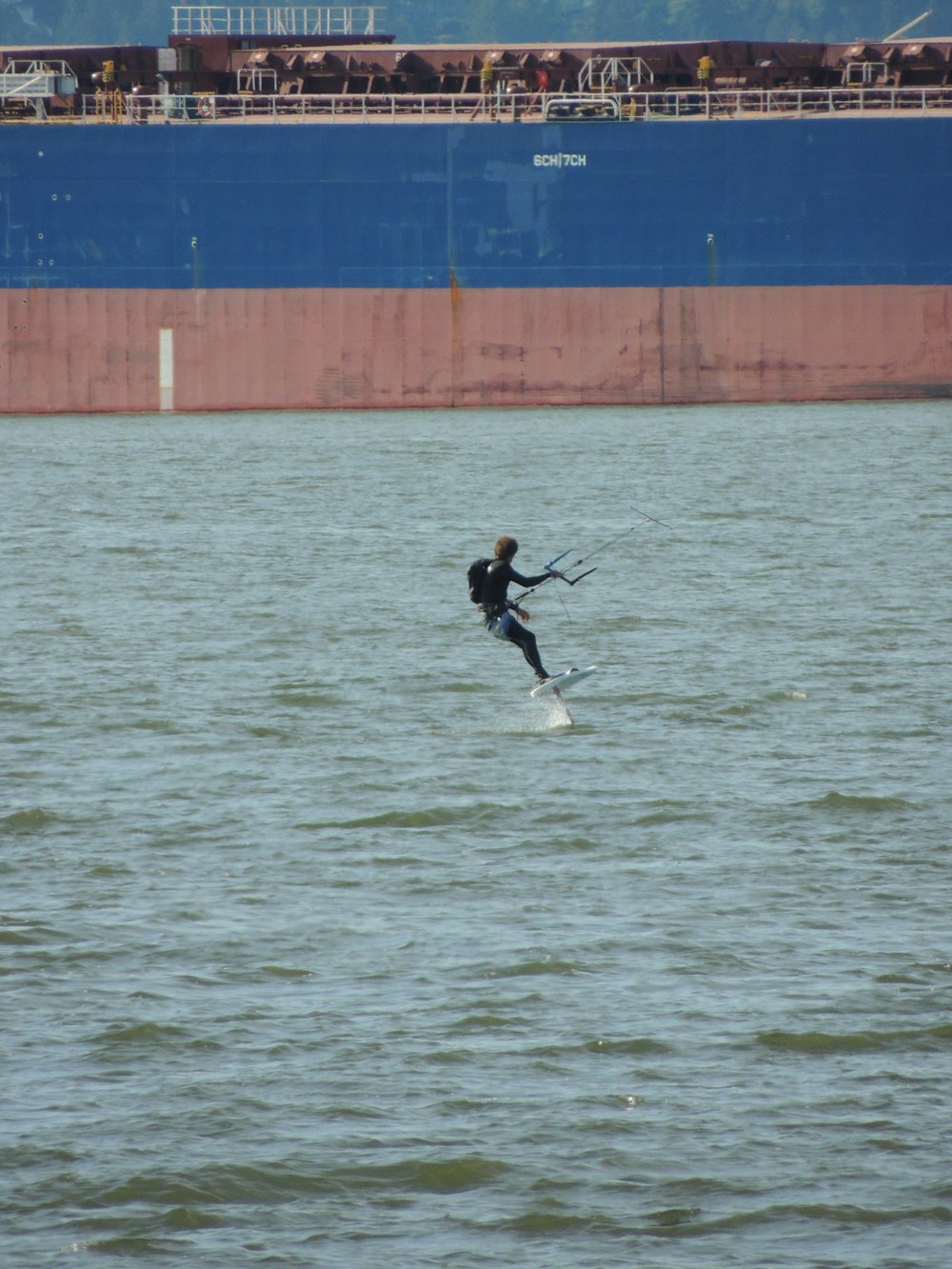 man in black jacket and white pants surfing on sea during daytime