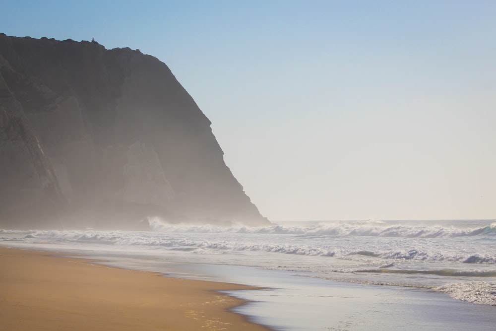 black rock formation on sea shore during daytime