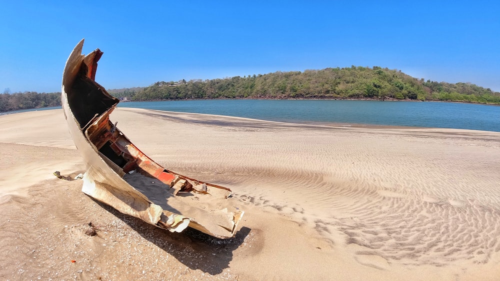 brown wooden boat on brown sand near body of water during daytime