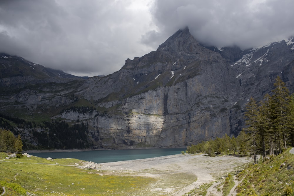 gray rocky mountain beside body of water during daytime