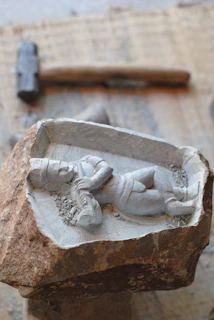Artisan carving tools resting beside a half-finished wooden figurine on a workbench