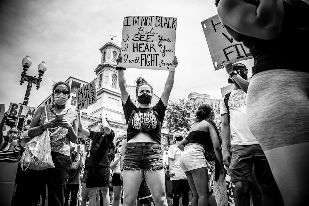 grayscale photo of people holding a signage