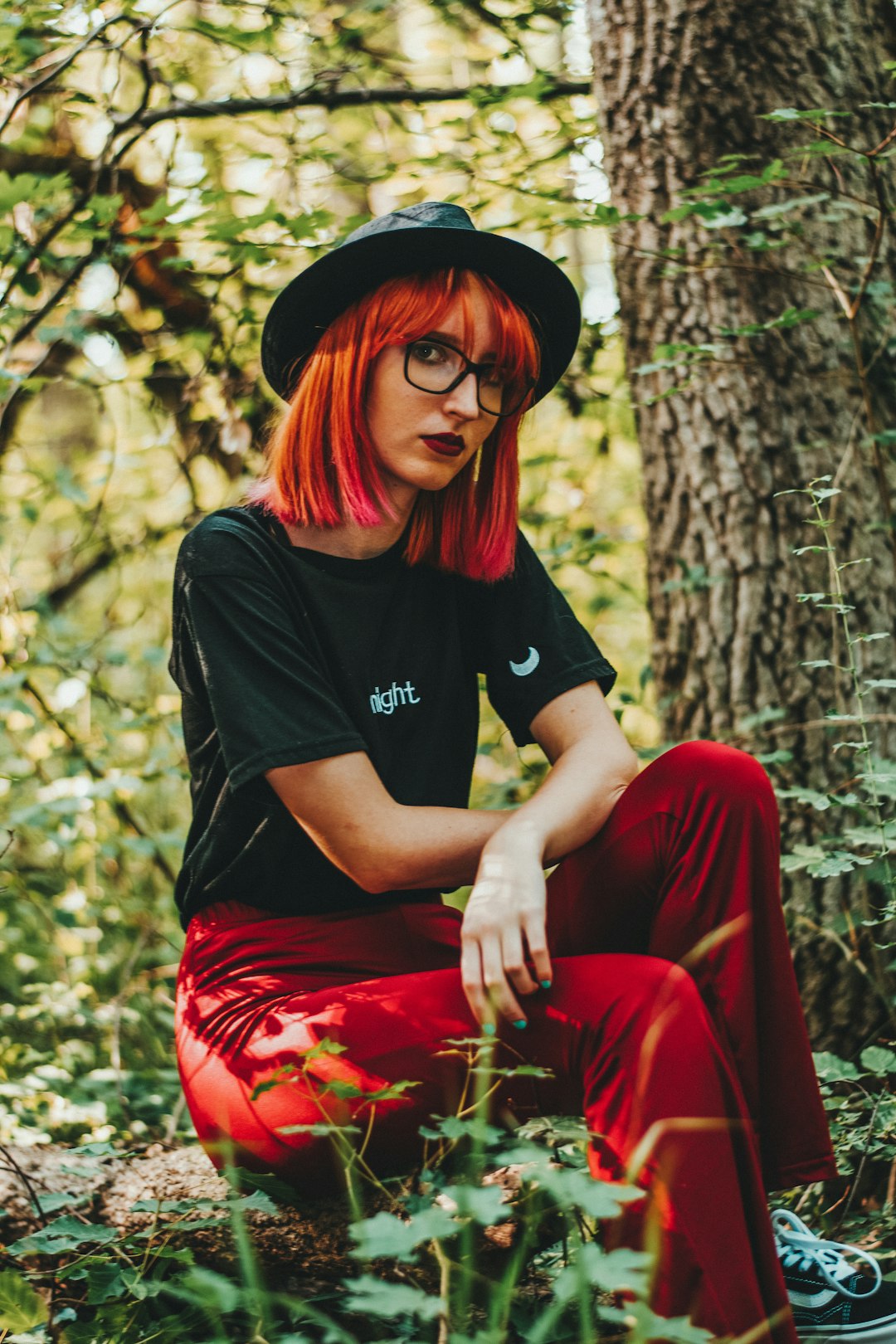 woman in black crew neck t-shirt and red pants sitting on tree