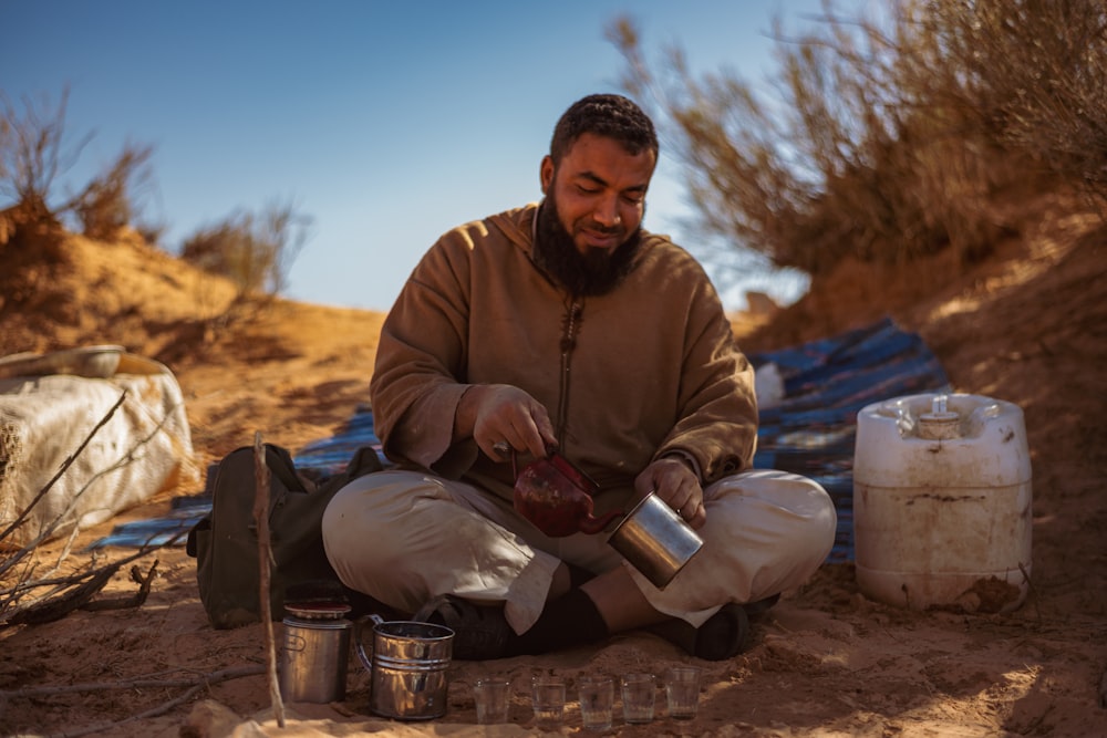 man in brown jacket sitting on sand during daytime