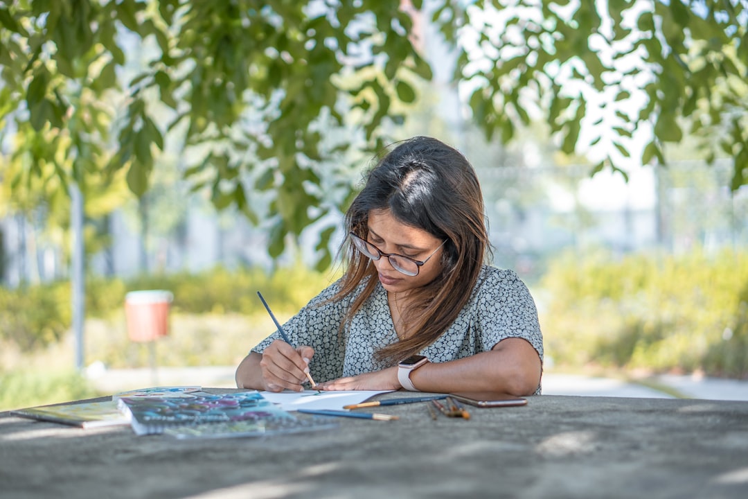 woman in blue and white polka dot shirt writing on white paper