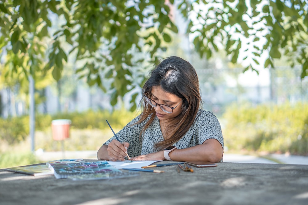 woman in blue and white polka dot shirt writing on white paper