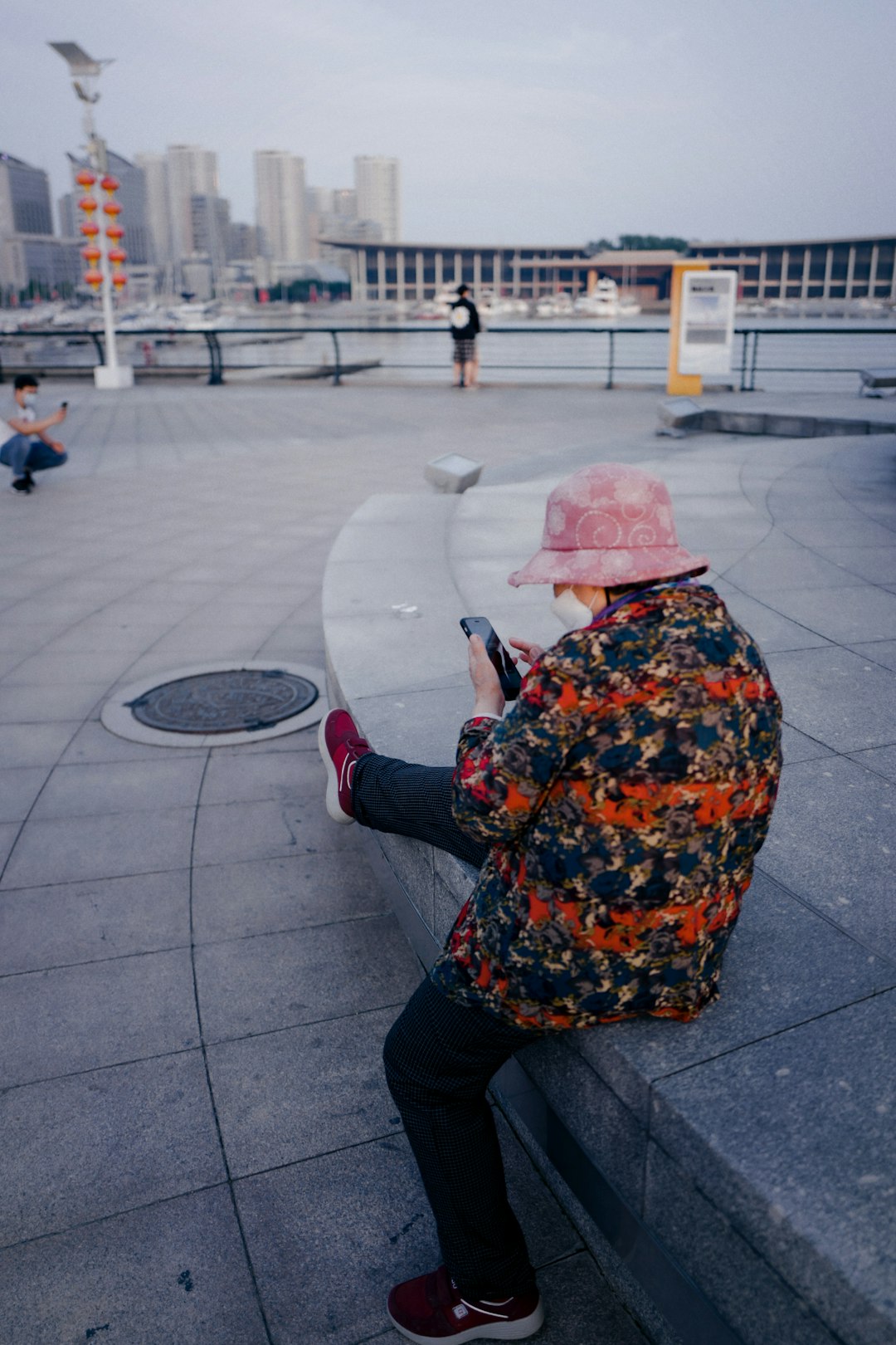 woman in black jacket and pink floral hijab holding smartphone