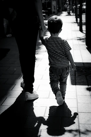 Happy parent holding hands with a child in trendy sneakers on a city sidewalk.