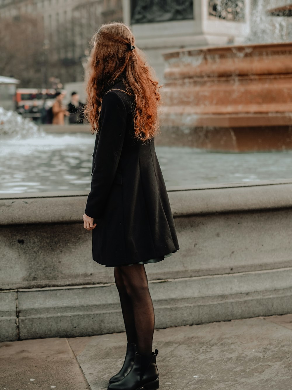 woman in black coat standing on concrete bridge during daytime