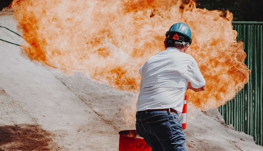 man in white shirt and blue denim jeans wearing black helmet standing on gray concrete road