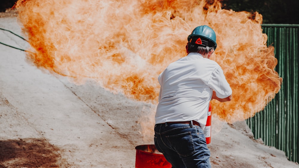 man in white shirt and blue denim jeans wearing black helmet standing on gray concrete road