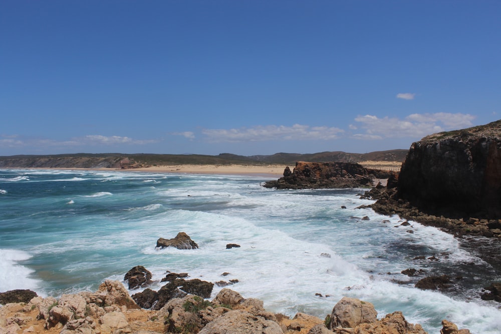 brown rock formation on sea under blue sky during daytime