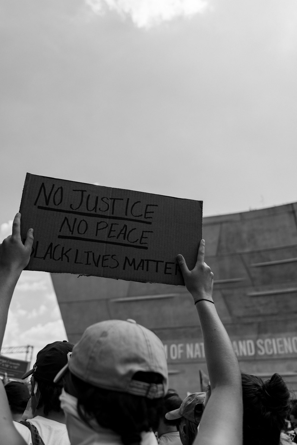 grayscale photo of person holding welcome to the beach signage