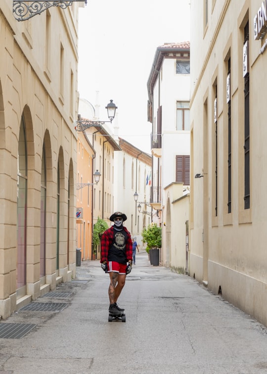 woman in black and red jacket walking on sidewalk during daytime in Vicenza Italy