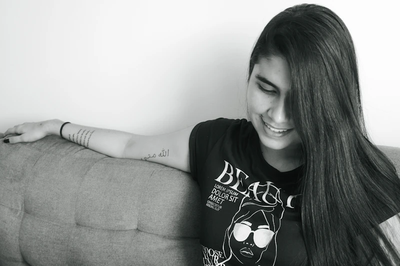 woman in a black and white t-shirt sitting on a brown sofa
