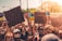 A large group of people gathered outdoors, holding various signs with messages advocating for social justice. Some signs include phrases like 'Black Lives Matter' and 'Counselors Over Cops.' Many participants are wearing masks, reflecting a sense of unity in protest.