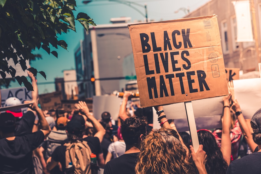 people holding brown wooden signage during daytime