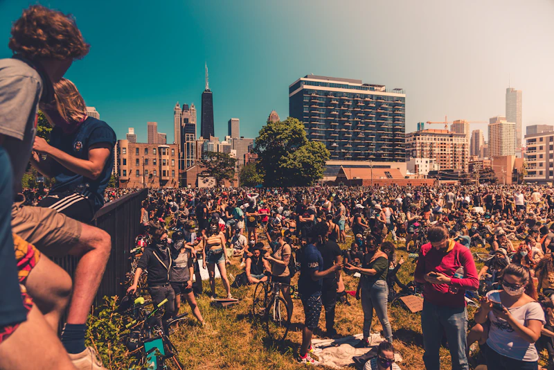 A crowd gathered on Chicago parkland with high-rises in the distance, evoking a festival setting