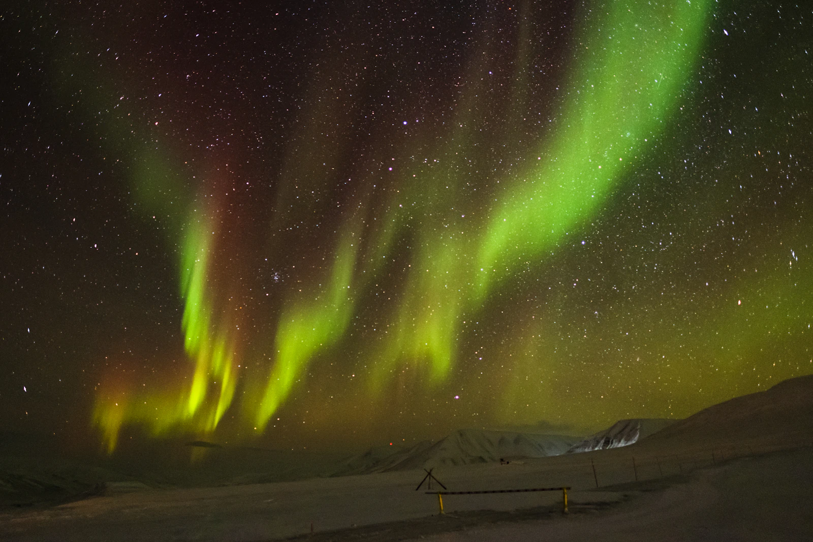 Green and yellow aurora spreading across the night sky above Longyearbyen, Svalbard