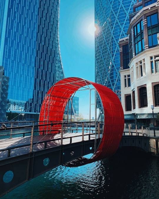 red arch near high rise building during daytime in Canary Wharf United Kingdom