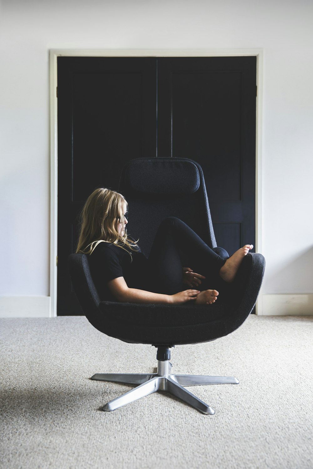 mulher no vestido preto sentado na cadeira de rolamento do escritório preto