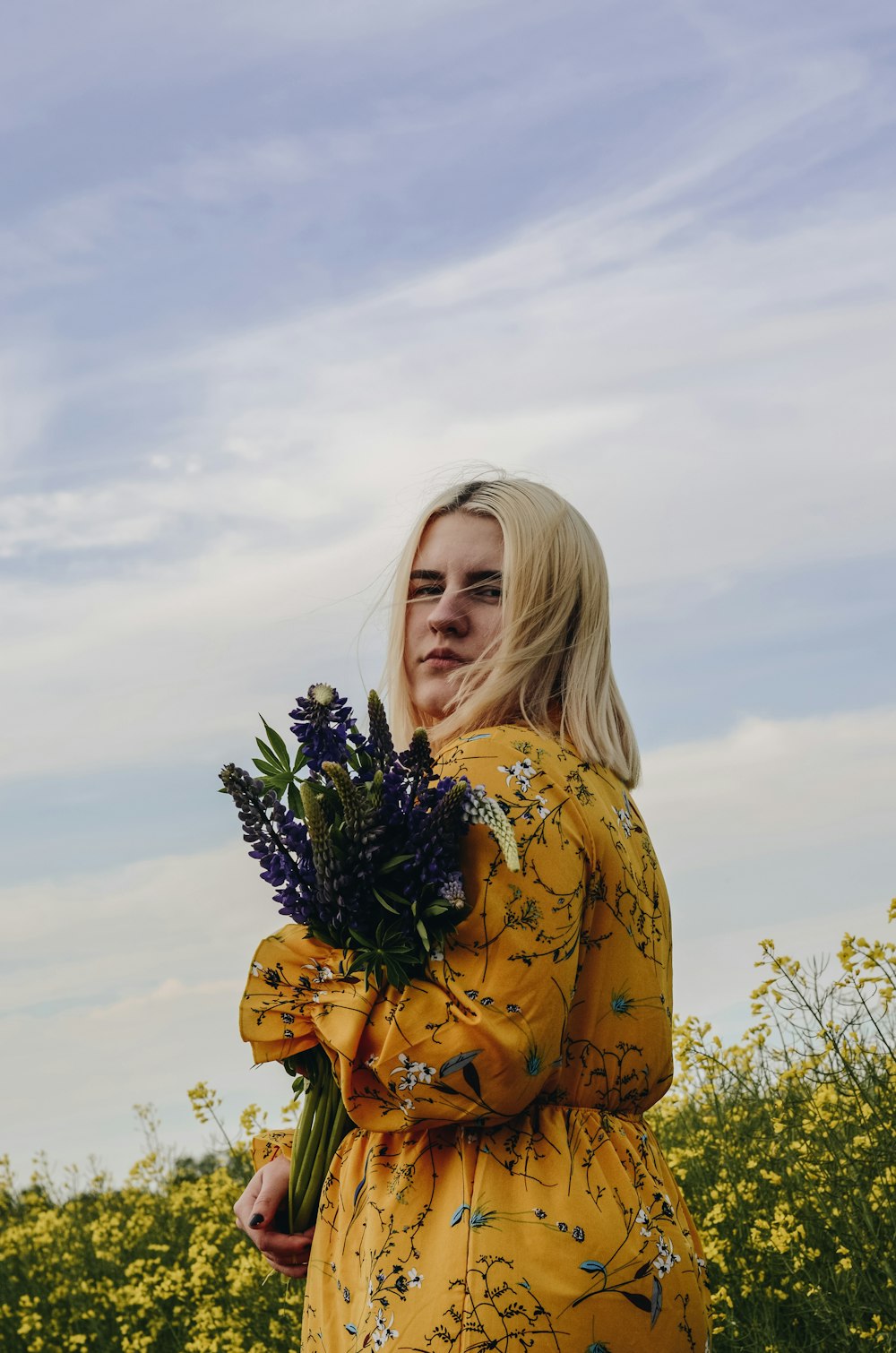 woman in yellow and black floral long sleeve shirt holding white flowers