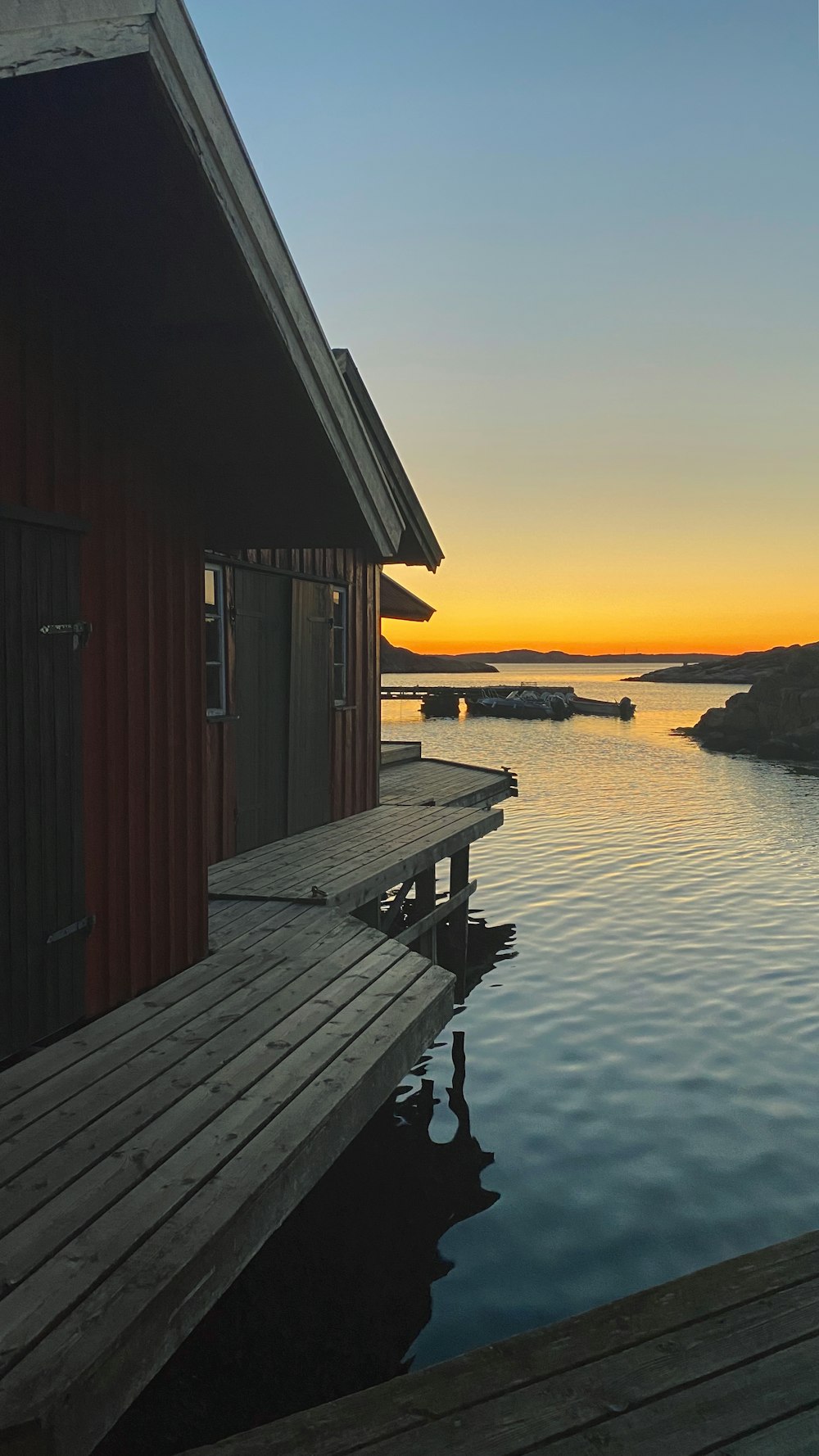 brown wooden house on sea dock during sunset