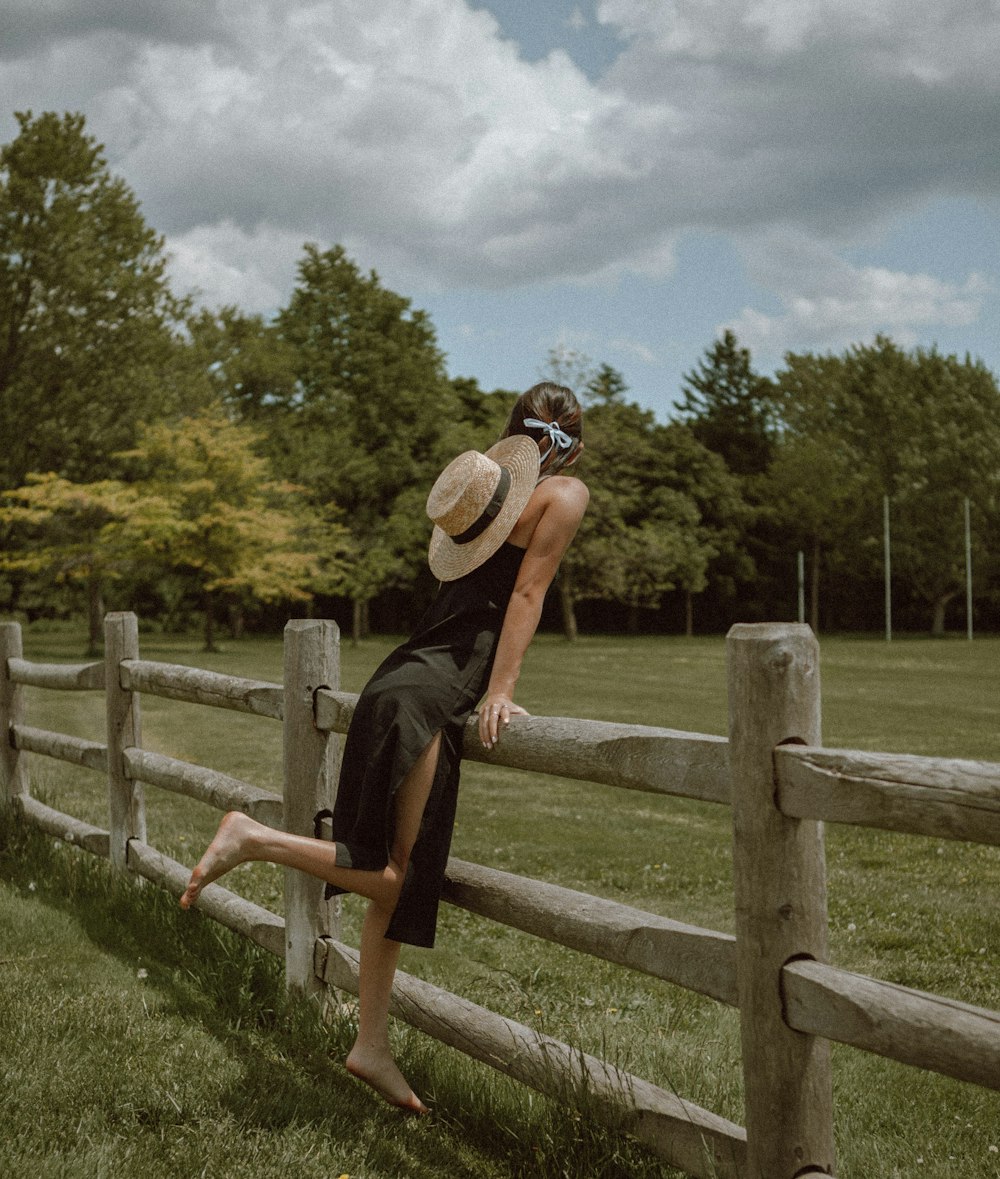 man in black tank top and black shorts wearing brown fedora hat standing on green grass