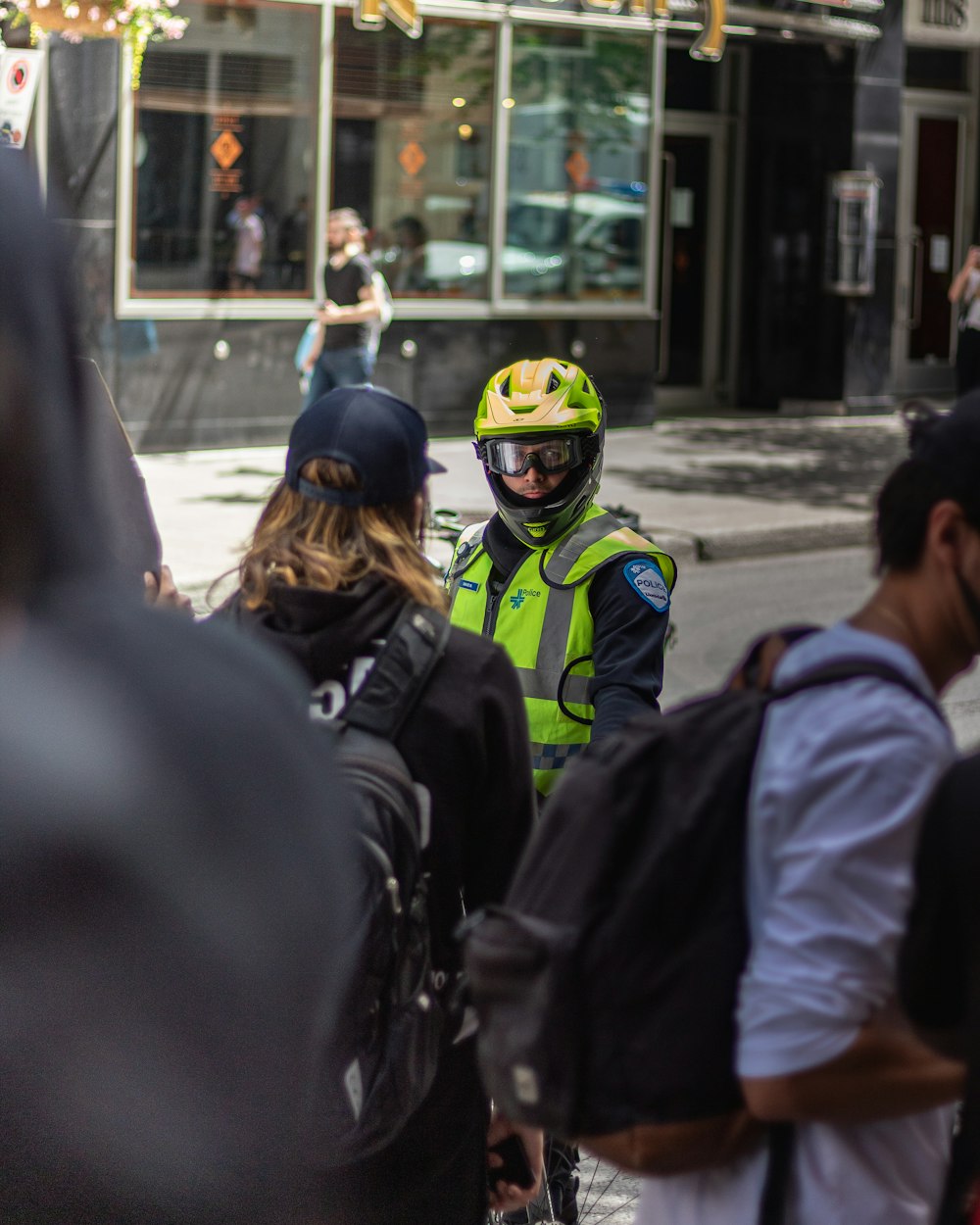 people in black and yellow helmet and black jacket walking on street during daytime