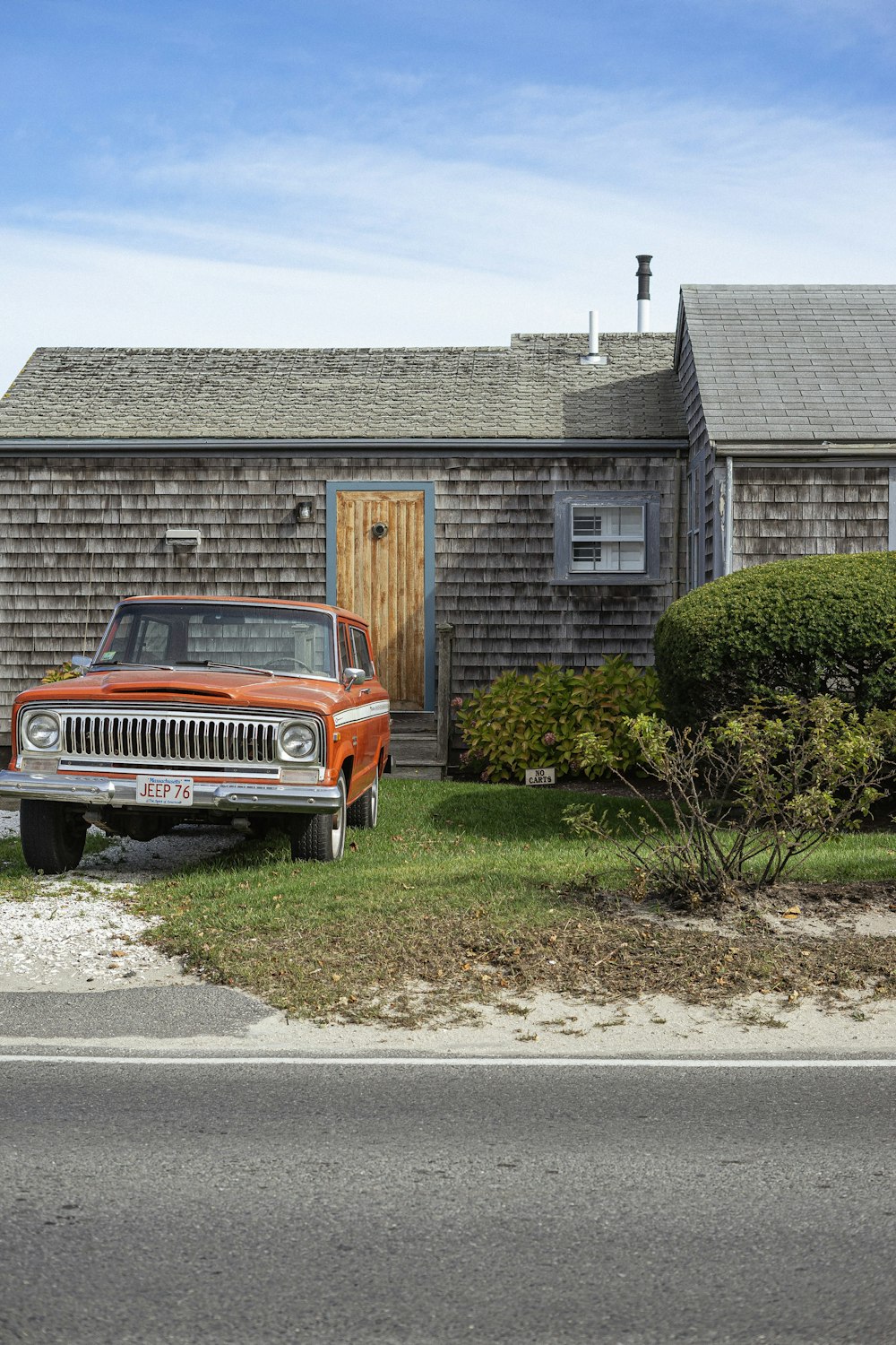 orange and white chevrolet car parked beside green plants during daytime