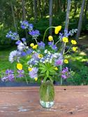 A serene forest backdrop with a ceramic vase holding wildflowers on a stump.