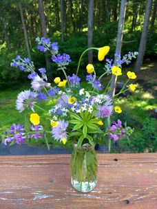 An elegant floral vase with subtle color variations, filled with fresh wildflowers.