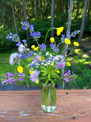 An elegant floral vase with subtle color variations, filled with fresh wildflowers.