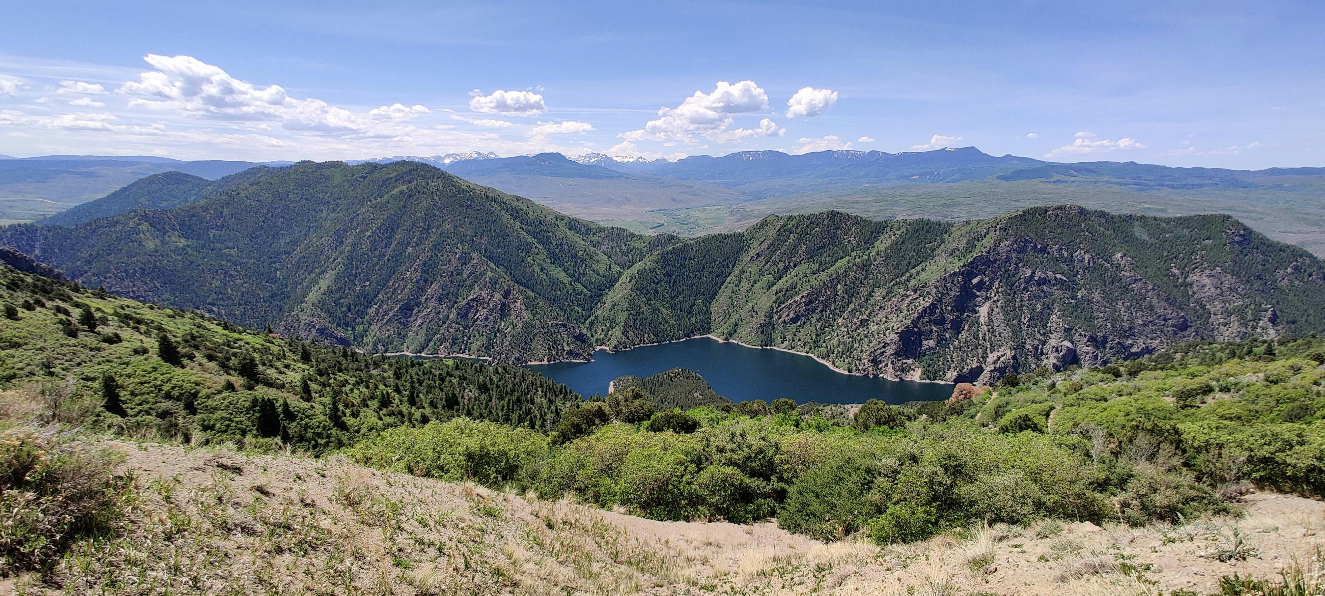 green mountains near lake under blue sky during daytime