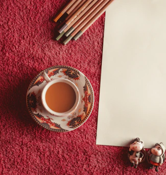 A serene pastel illustration of a tea cup surrounded by colouring pencils.