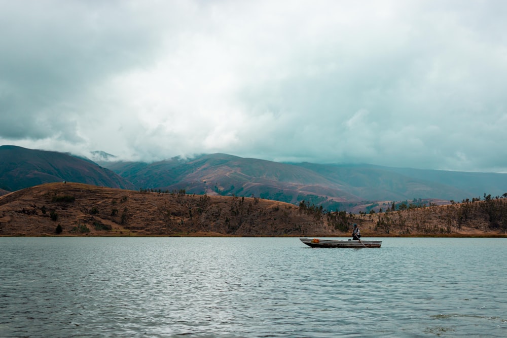 white boat on sea near mountain under white clouds during daytime