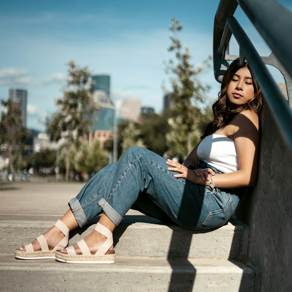 woman in blue denim jeans sitting on concrete bench during daytime