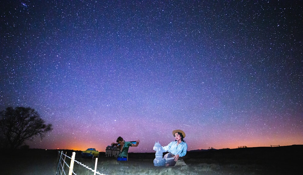man and woman sitting on beach during night time
