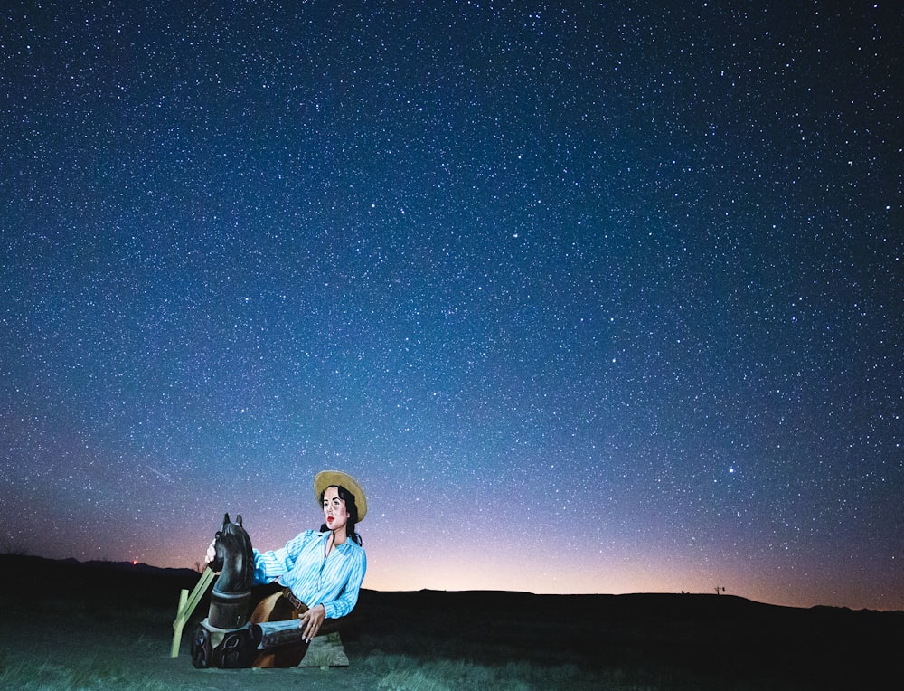 man in blue jacket sitting on black camping chair under blue sky during night time