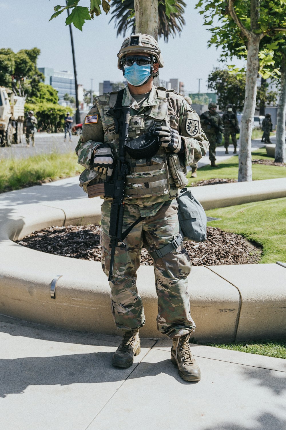 uomo in uniforme mimetica verde e marrone che tiene il fucile marrone
