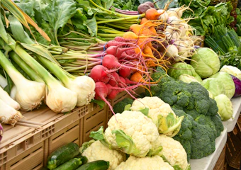 Fresh cauliflower, radishes, and onions at a market stall