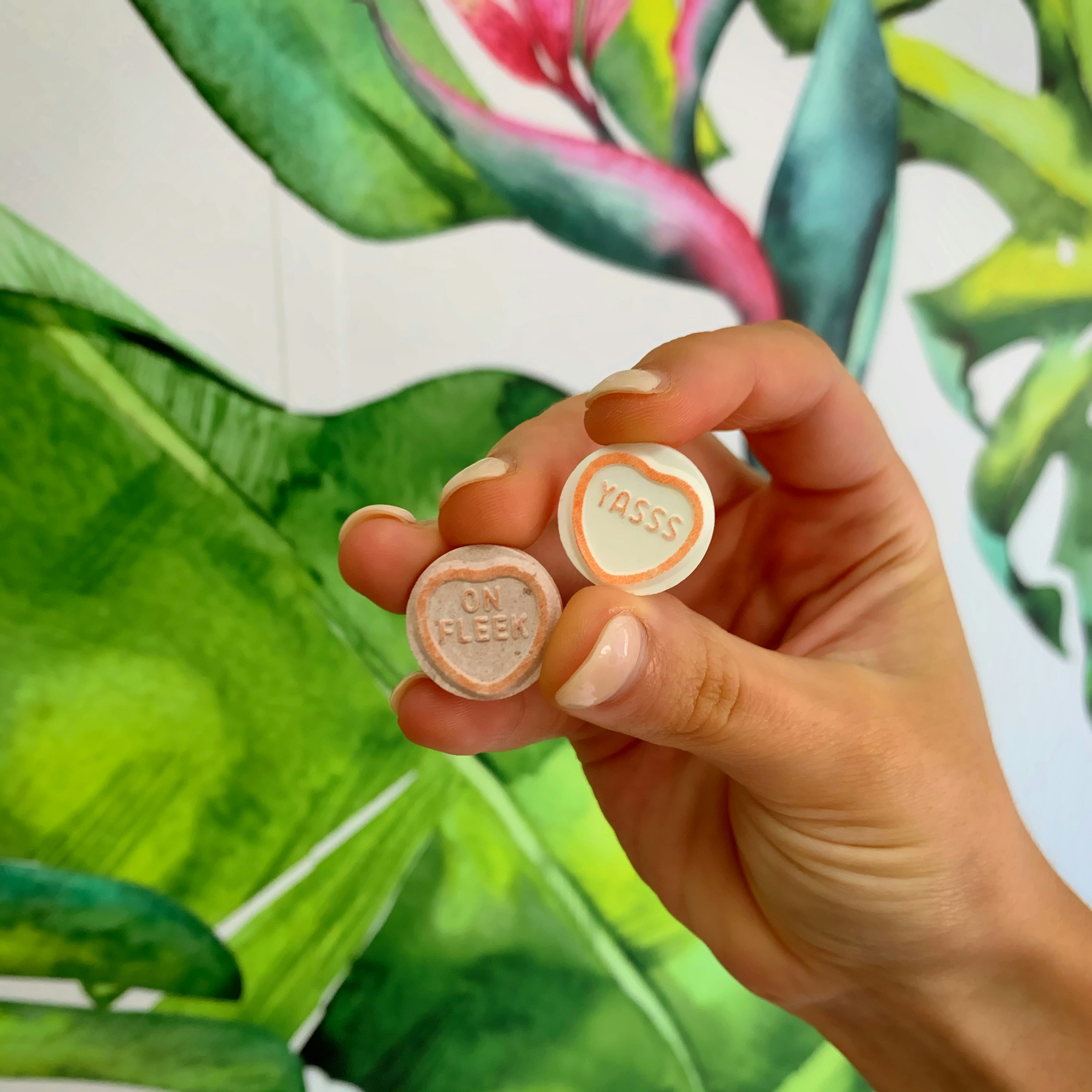 'Yas' and 'On Fleek' Valentines Day candy with tropical feature wall in background.