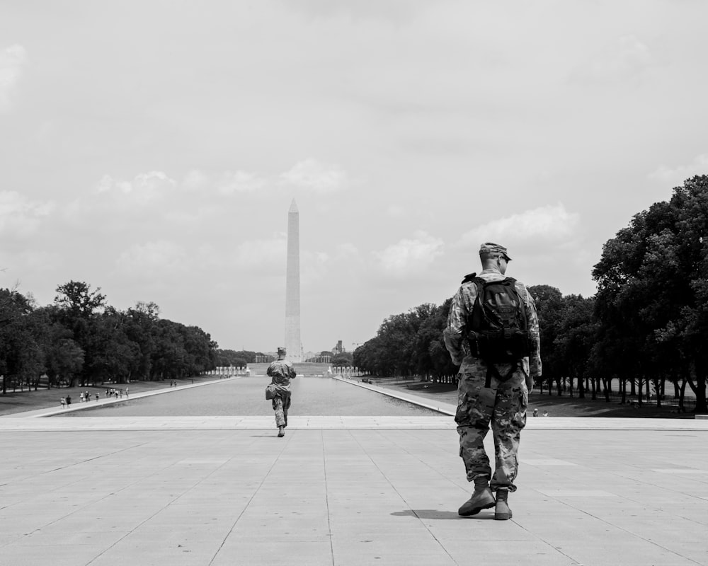 homme en veste noire et pantalon marchant sur le parc