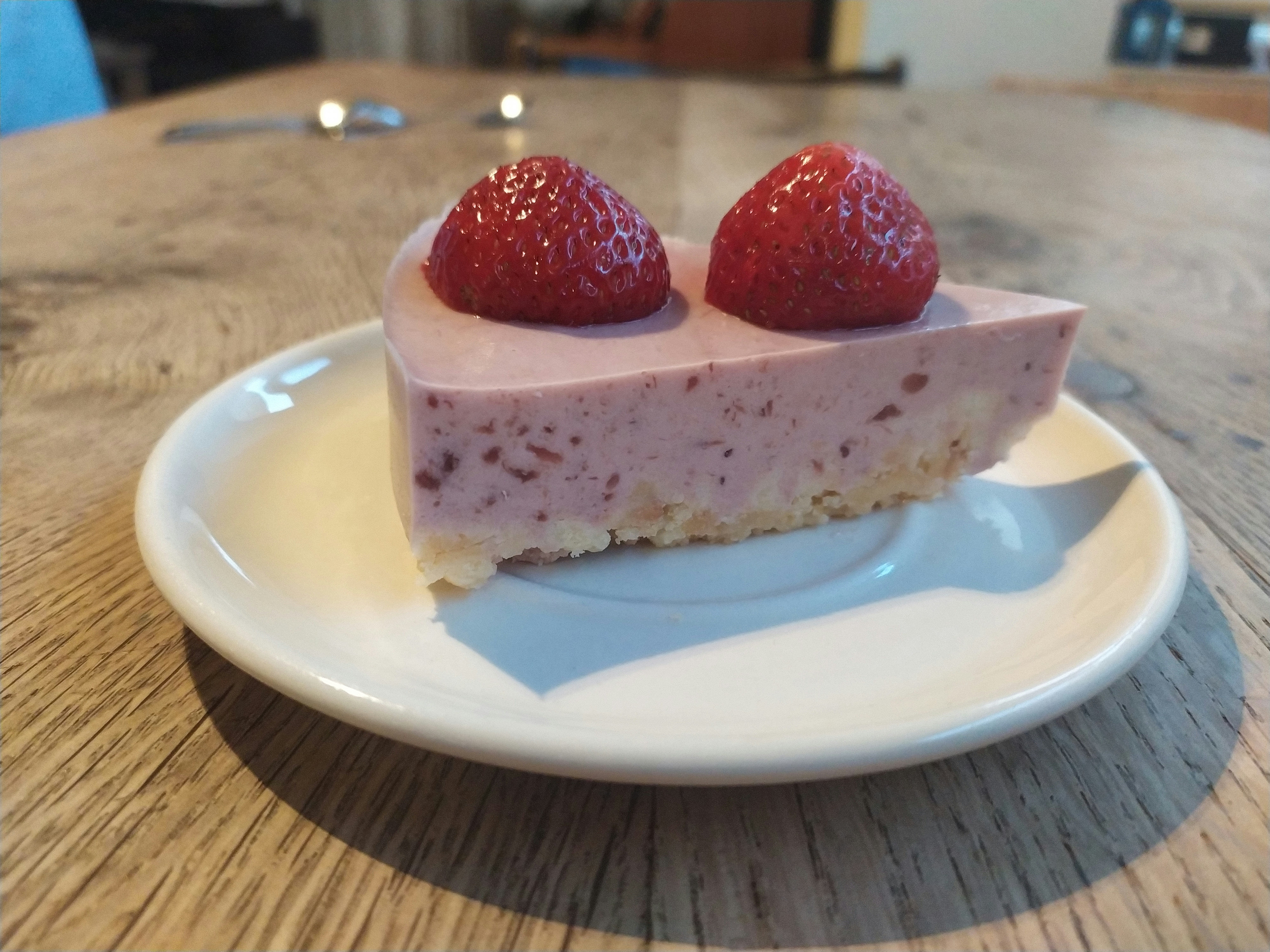 Elegant cheesecake slice topped with fresh strawberries and pink rose coulis drizzle