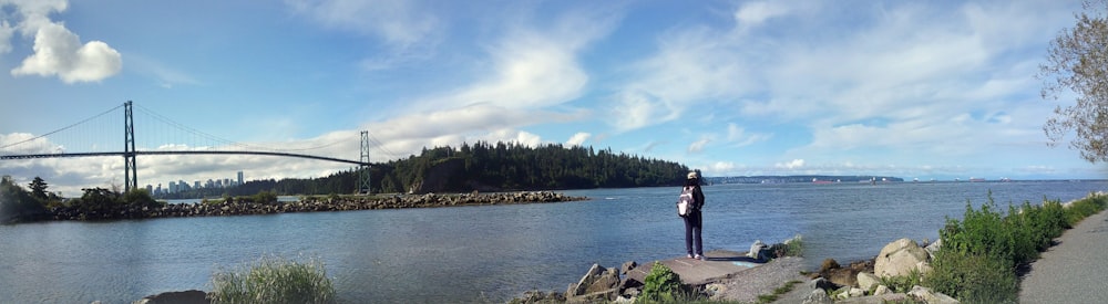 man and woman standing on rock near body of water during daytime