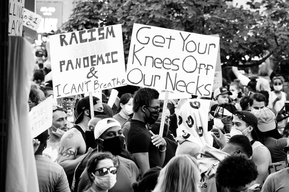 grayscale photo of people holding a signage