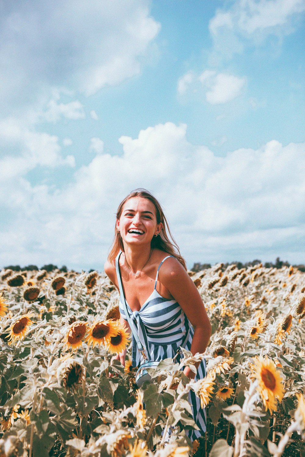 woman in white and blue stripe tank top standing on brown dried leaves during daytime