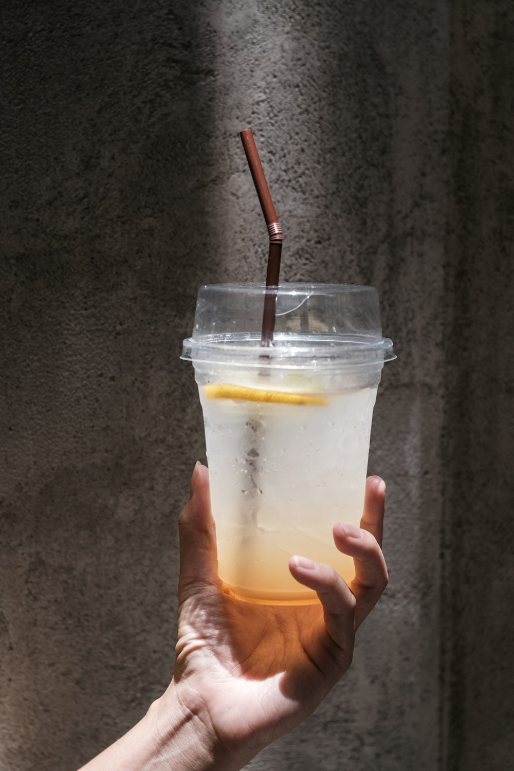 person holding clear drinking glass with yellow liquid